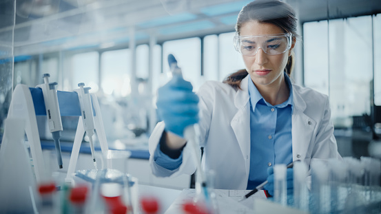 Portrait of a Female Healthcare science practitioner in Goggles Using Micro Pipette for Test Analysis.