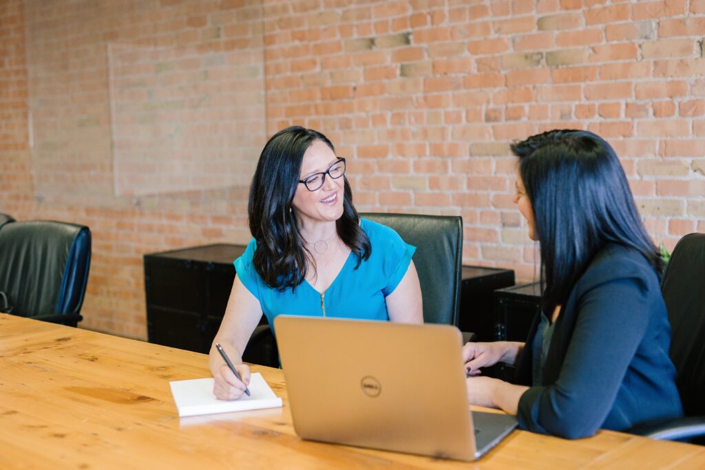 An apprentice and their Apprentice Network rep conversing by a desk with a Dell laptop open